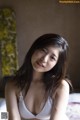 A woman in a white bra sitting on a bed.
