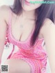 A woman in a pink dress sitting on a bed.