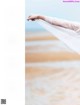 A woman in a white dress holding a white veil over her head.