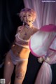 A woman in a pink lingerie holding a pink umbrella.