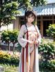 A woman in a white and red kimono standing in a garden.