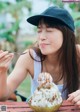 A woman sitting at a table eating an ice cream cone.