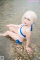 A woman in a blue and white bikini sitting in the water.