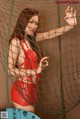 A woman in a red dress standing behind a net.