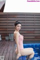 A woman in a pink bathing suit sitting on the edge of a pool.