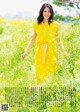 A woman in a yellow dress walking through a field of flowers.