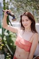 A woman in a pink bikini holding a shower head.