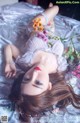 A woman laying on a bed with flowers in her hair.