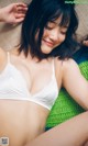 A woman in a white bra laying on a green blanket.
