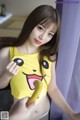 A woman in a yellow shirt holding a banana.