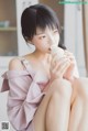 A woman sitting on the floor drinking from a bottle.