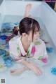 A woman laying in a bathtub filled with water and flowers.