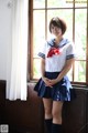 A woman in a sailor outfit posing by a window.