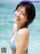 A woman in a blue bikini standing in the ocean.