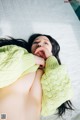 A woman laying on top of a bed wearing a green sweater.