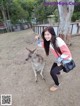 A woman kneeling down next to a kangaroo in a field.