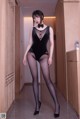 A woman in a black bodysuit and high heels posing for a picture.