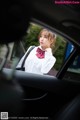 A woman in a white shirt and red bow tie sitting in a car.