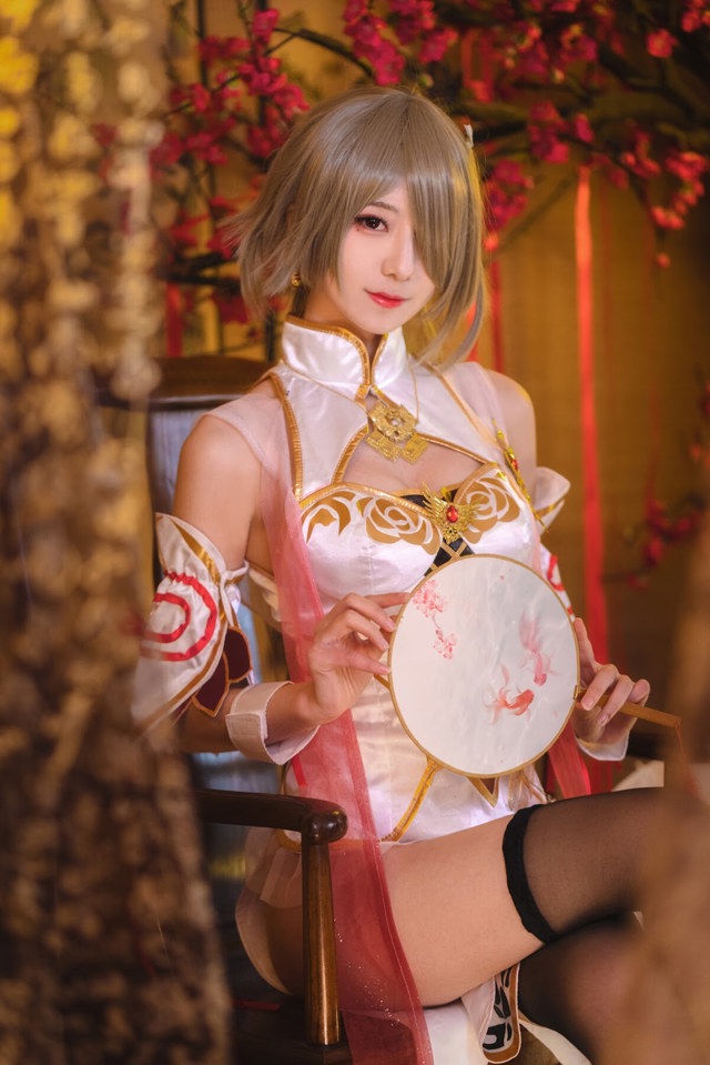 A woman in a white dress holding a drum.