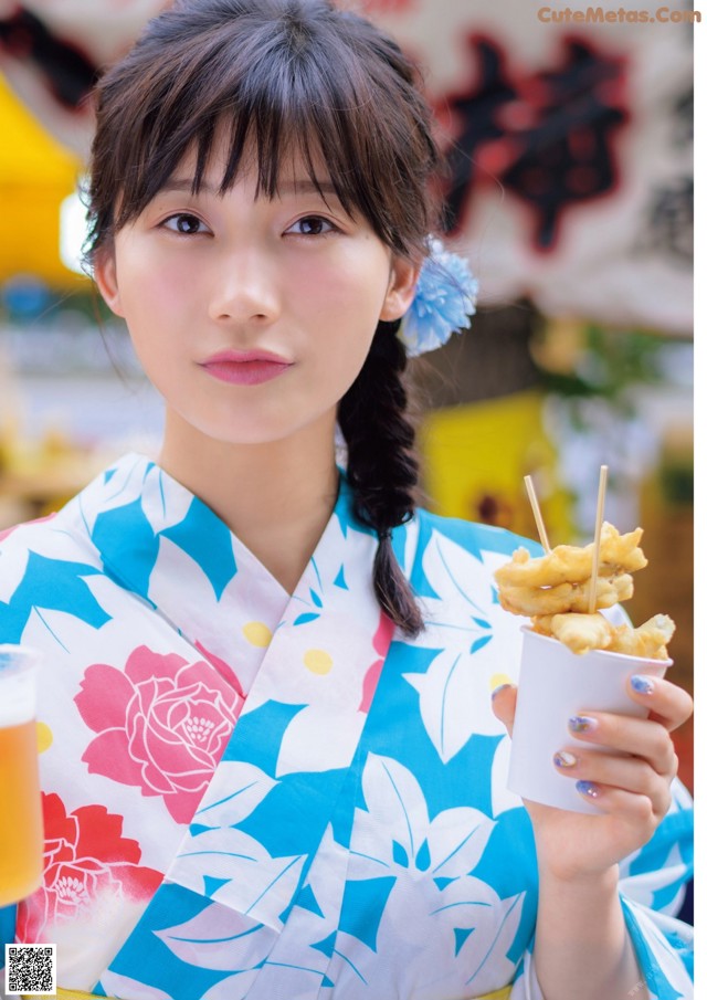 A woman in a kimono holding a cup of food.