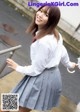 A woman in a school uniform holding an umbrella.