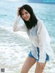 A woman standing on a beach next to the ocean.