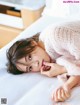 A woman laying on a bed with her hand on her chin.