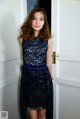 A woman standing in front of a door wearing a blue dress.