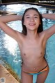 A young woman in a bikini posing by a swimming pool.