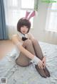 A woman in a bunny costume sitting on a bed.