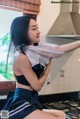 A woman in a black and white dress is posing in a kitchen.