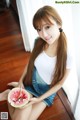 A woman sitting on the floor eating a slice of watermelon.