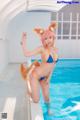 A woman in a bikini with a fox tail in a pool.