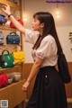 A woman standing in front of a shelf of handbags.