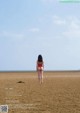 A woman in a red bathing suit standing on a beach.