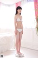 A woman in a white bikini standing on a scale.