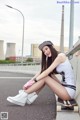 A woman sitting on a skateboard on the side of a road.